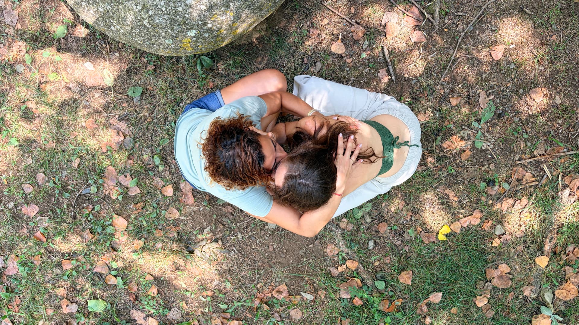 Familia abrazada sobre hojas y tierra, vista cenital